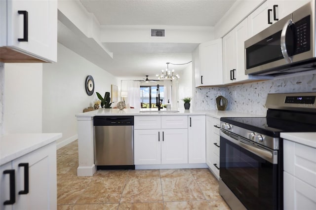 kitchen featuring kitchen peninsula, white cabinets, a textured ceiling, a chandelier, and stainless steel appliances