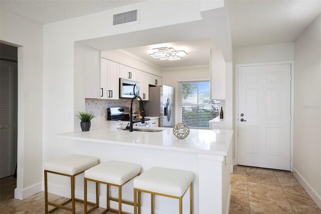 6291 Bahia Del Mar Cir Unit 103, Saint Petersburg, FL 33715 - kitchen with light countertops, a breakfast bar, visible vents, a peninsula, and appliances with stainless steel finishes