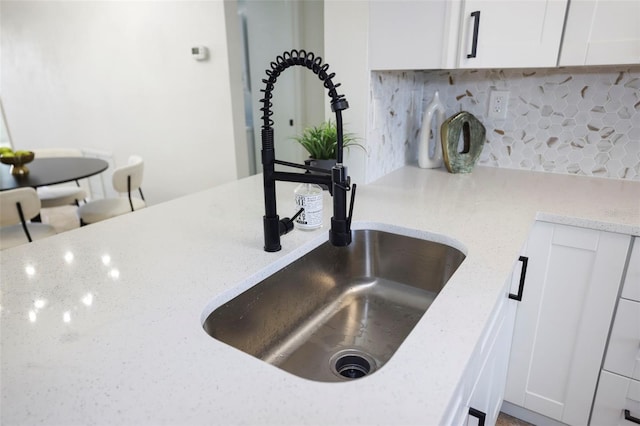 room details featuring tasteful backsplash, light stone countertops, and white cabinets