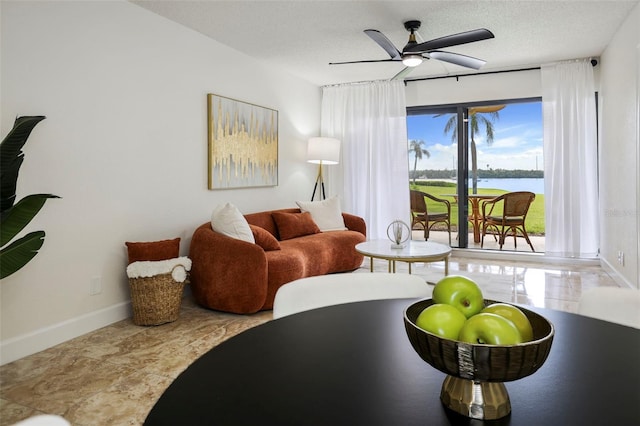 living room featuring a water view, ceiling fan, and a textured ceiling