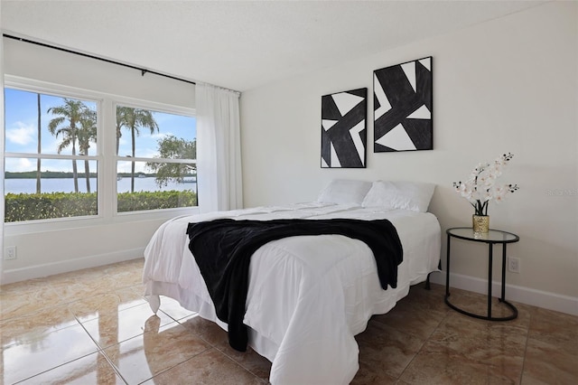 bedroom featuring a water view and tile patterned flooring