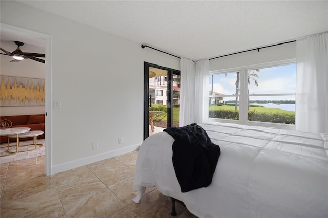 bedroom featuring a water view, ceiling fan, a textured ceiling, and access to exterior