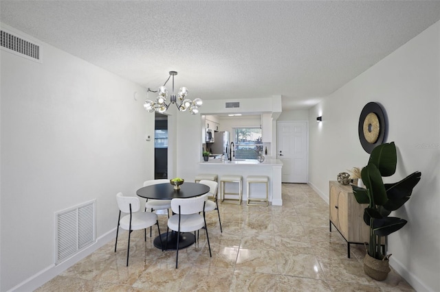 dining space featuring sink, a textured ceiling, and an inviting chandelier