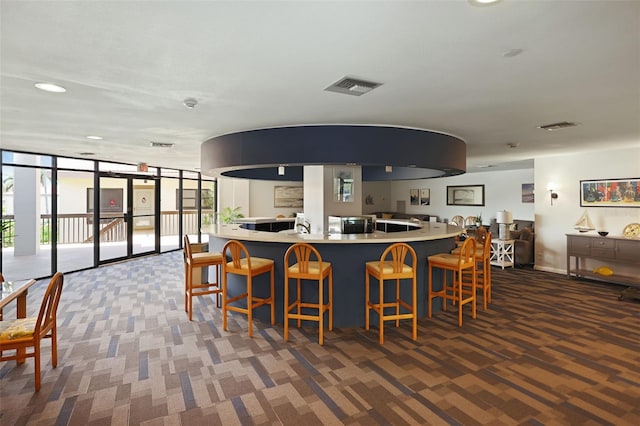 kitchen featuring a kitchen breakfast bar, expansive windows, and dark colored carpet