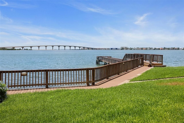 view of dock with a water view and a yard