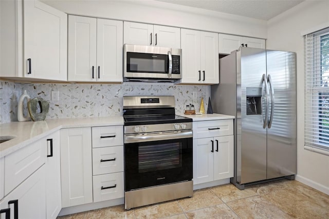 kitchen featuring backsplash, a textured ceiling, white cabinetry, stainless steel appliances, and light tile patterned floors