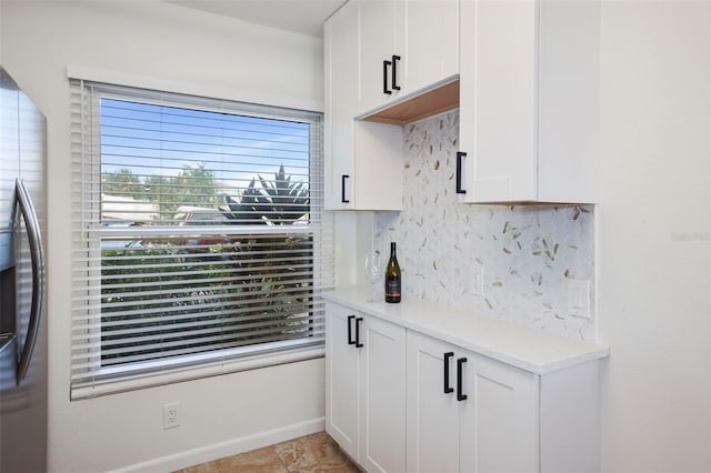 6291 Bahia Del Mar Cir Unit 103, Saint Petersburg, FL 33715 - kitchen featuring white cabinets, stainless steel fridge with ice dispenser, backsplash, light countertops, and baseboards
