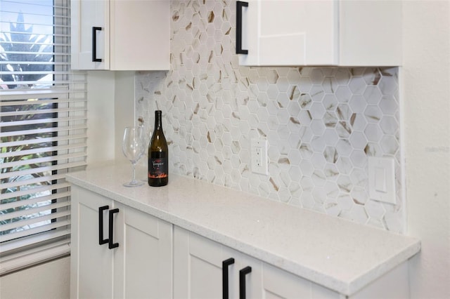 interior space featuring white cabinetry, light stone counters, and backsplash