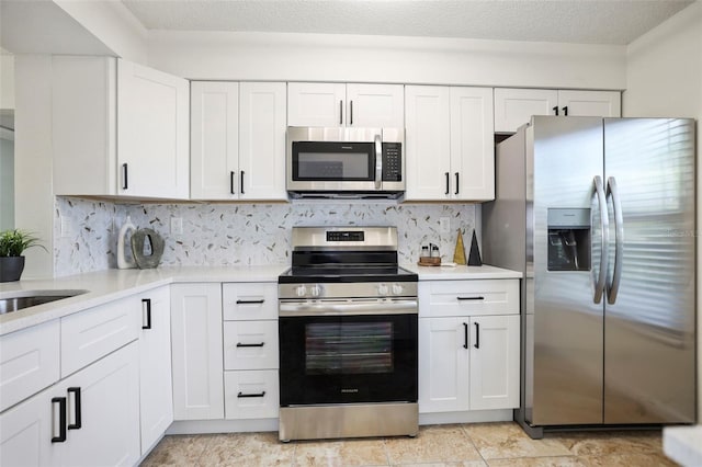 kitchen featuring a textured ceiling, white cabinetry, stainless steel appliances, and backsplash