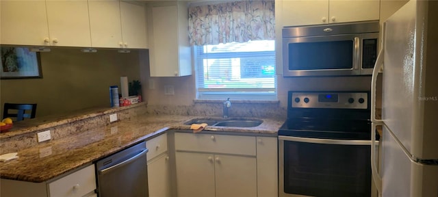 kitchen with light stone counters, white cabinets, stainless steel appliances, and sink