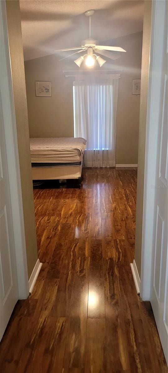 unfurnished bedroom featuring ceiling fan, lofted ceiling, and dark hardwood / wood-style flooring