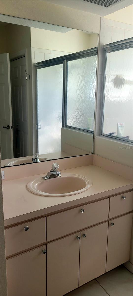 bathroom featuring tile patterned flooring, an enclosed shower, and vanity