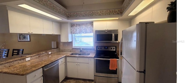 4432 Whitton Way, New Port Richey, FL 34653 - kitchen with appliances with stainless steel finishes, white cabinetry, a peninsula, and light stone counters