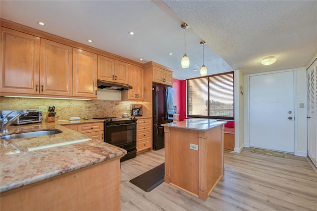 kitchen featuring pendant lighting, sink, a center island, light stone counters, and black appliances