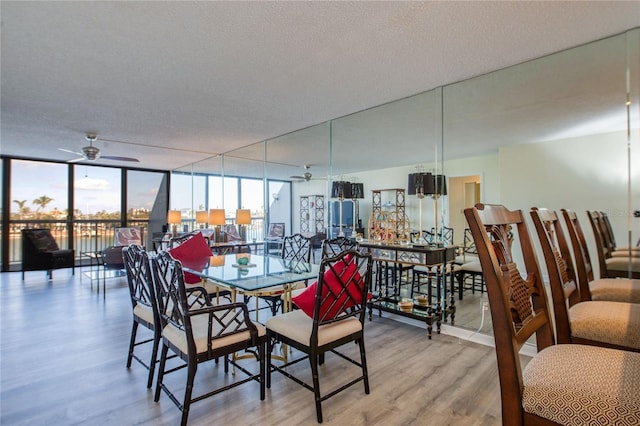 dining room featuring ceiling fan, a textured ceiling, light wood-type flooring, and a wall of windows