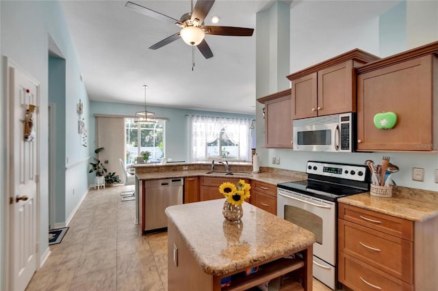 kitchen with ceiling fan with notable chandelier, appliances with stainless steel finishes, decorative light fixtures, and a kitchen island