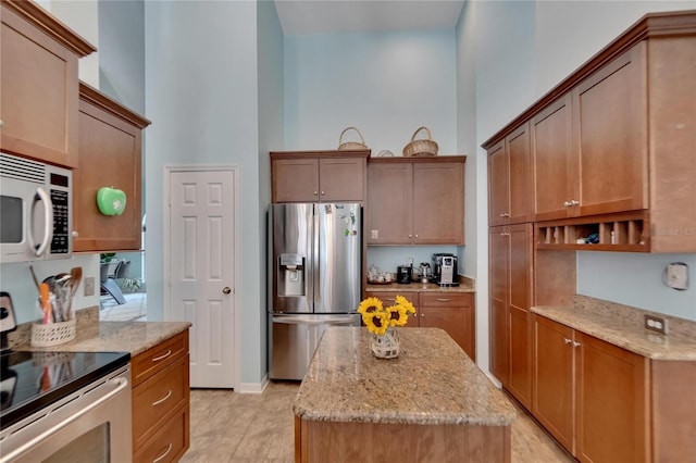 kitchen featuring stainless steel appliances, light stone counters, light tile patterned floors, and a kitchen island