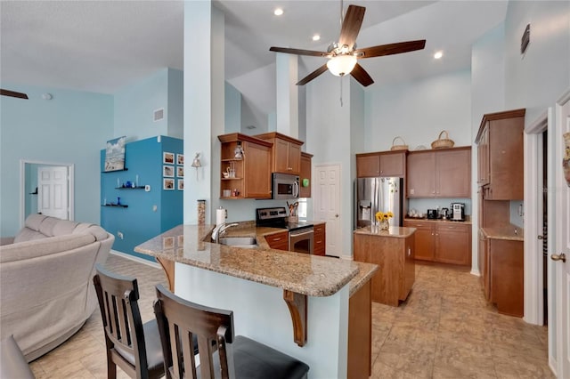 kitchen featuring appliances with stainless steel finishes, kitchen peninsula, ceiling fan, and high vaulted ceiling