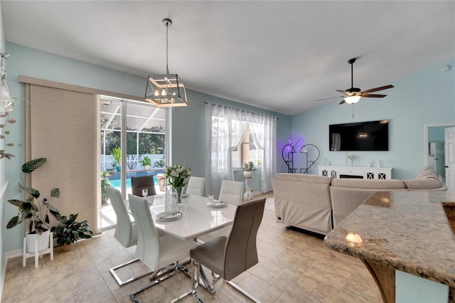 tiled dining room featuring ceiling fan with notable chandelier and lofted ceiling