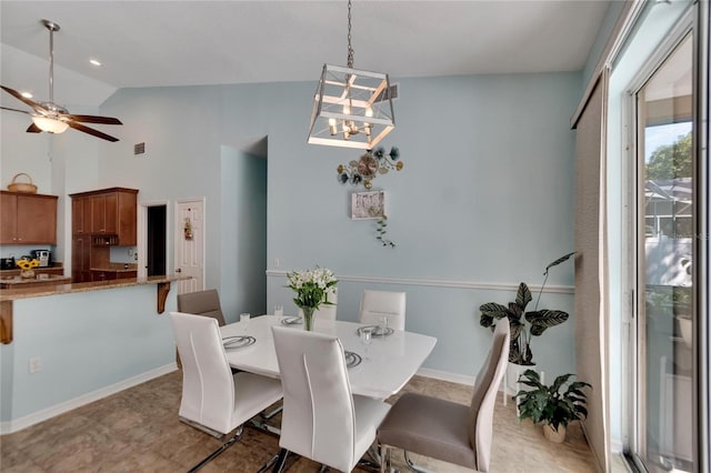 dining area featuring ceiling fan with notable chandelier and high vaulted ceiling