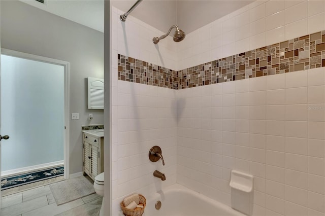 full bathroom with tiled shower / bath, vanity, and toilet