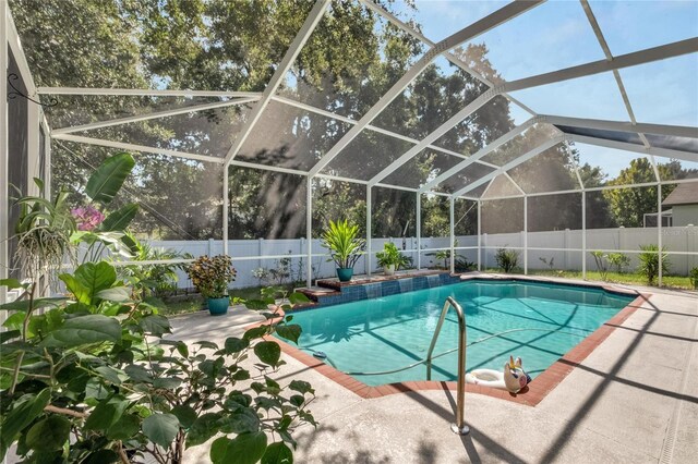 view of swimming pool featuring glass enclosure and a patio area