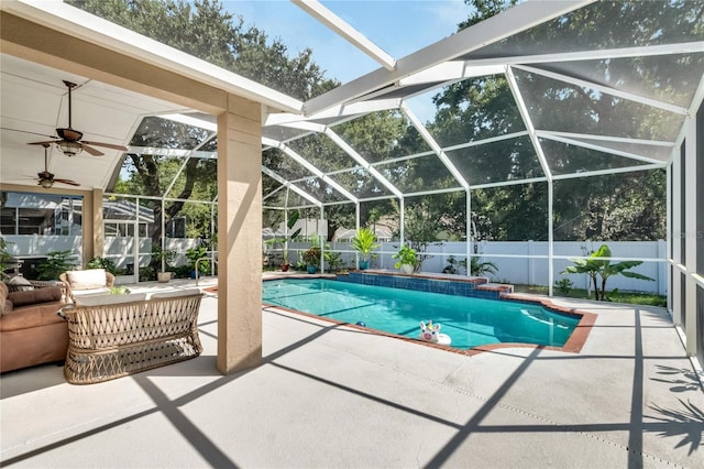 view of pool featuring a patio, glass enclosure, and ceiling fan