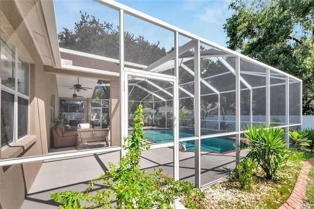 view of swimming pool with ceiling fan, glass enclosure, and a patio area