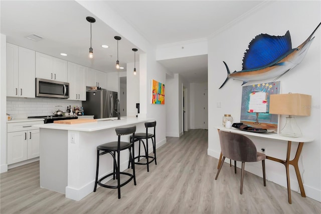 kitchen featuring appliances with stainless steel finishes, light wood-type flooring, a breakfast bar area, and white cabinets