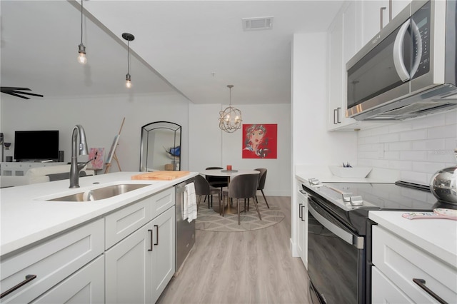 kitchen featuring hanging light fixtures, decorative backsplash, white cabinetry, stainless steel appliances, and sink