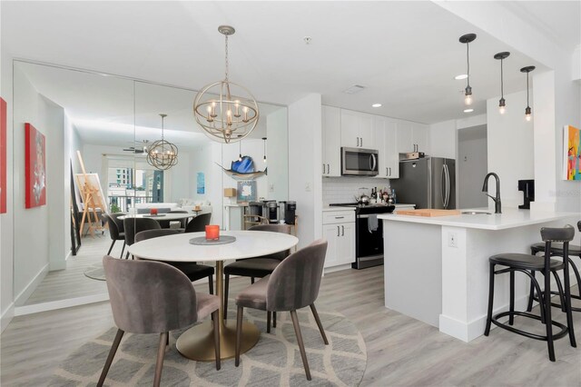 dining area with an inviting chandelier, light wood-type flooring, and sink