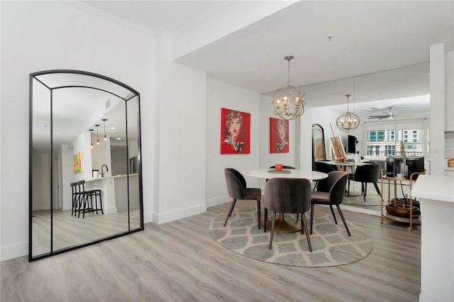 dining space featuring ceiling fan with notable chandelier, light hardwood / wood-style flooring, and ornamental molding