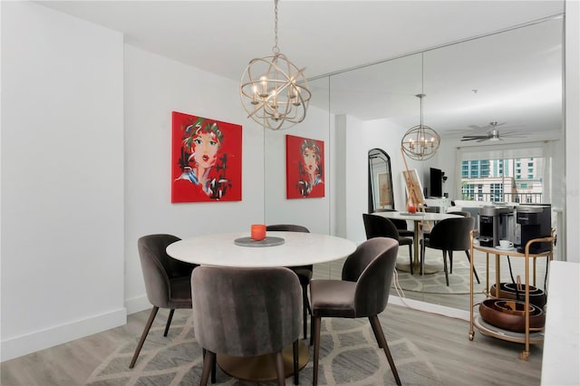 dining room with hardwood / wood-style flooring and ceiling fan with notable chandelier