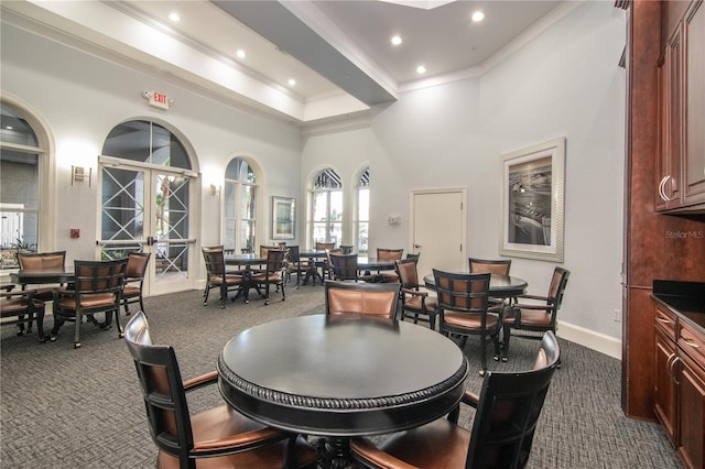 dining room featuring french doors, dark colored carpet, crown molding, and a high ceiling