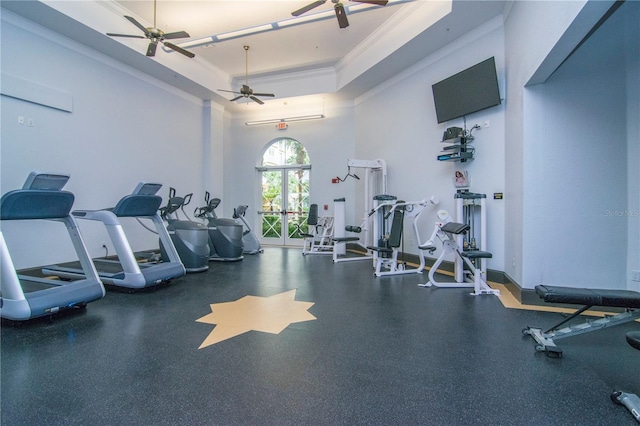 workout area with crown molding, a tray ceiling, a towering ceiling, and ceiling fan