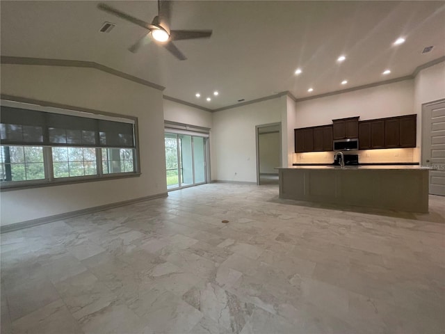 kitchen with a center island with sink, a towering ceiling, crown molding, ceiling fan, and sink