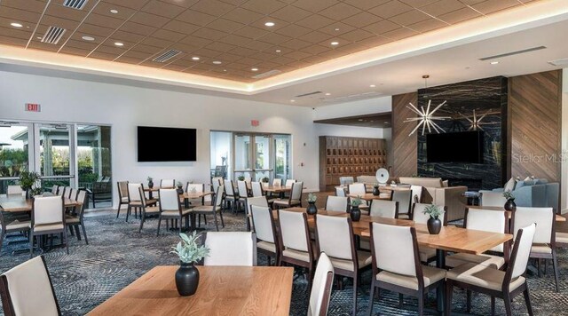 dining space with a high ceiling, a tray ceiling, a wealth of natural light, and wood walls