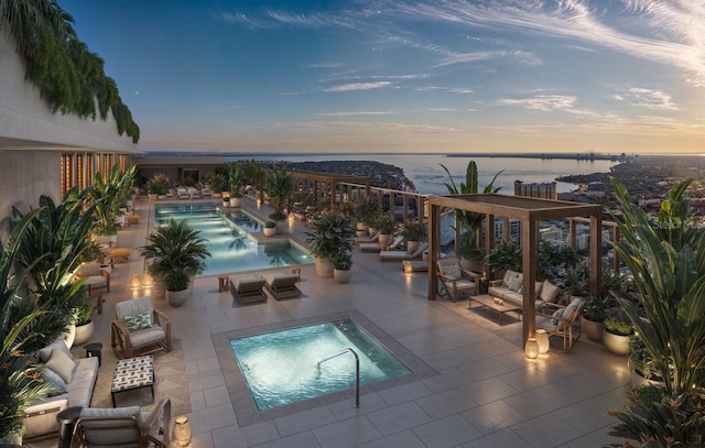 pool at dusk with a hot tub, a water view, an outdoor living space, and a patio