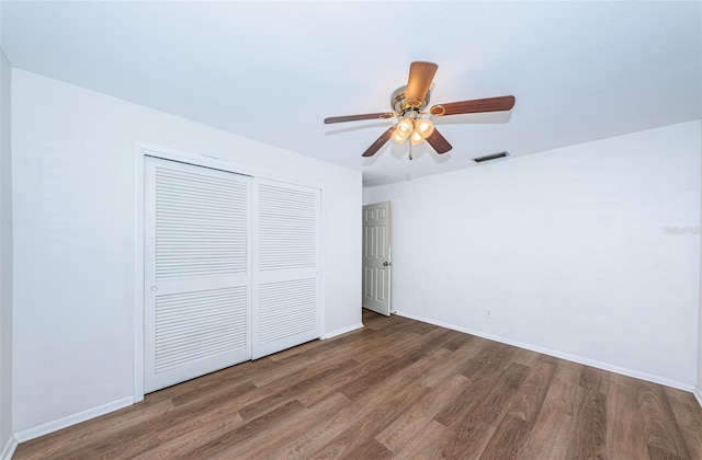 unfurnished bedroom with dark wood-type flooring, ceiling fan, and a closet