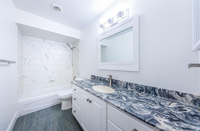 full bathroom featuring vanity, tiled shower / bath, hardwood / wood-style flooring, and toilet