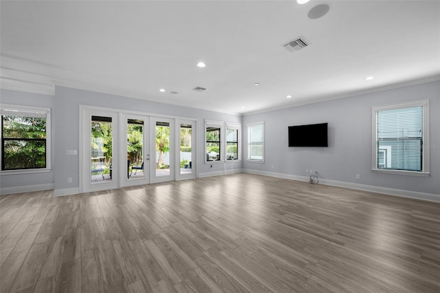 unfurnished living room featuring ornamental molding, french doors, and light wood-type flooring