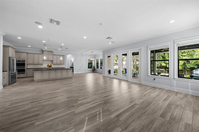 unfurnished living room featuring ornamental molding, light wood-type flooring, and french doors