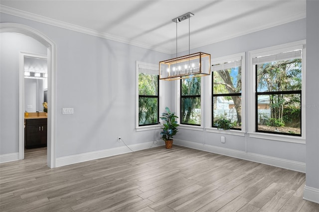 unfurnished dining area with crown molding, a chandelier, and light hardwood / wood-style flooring