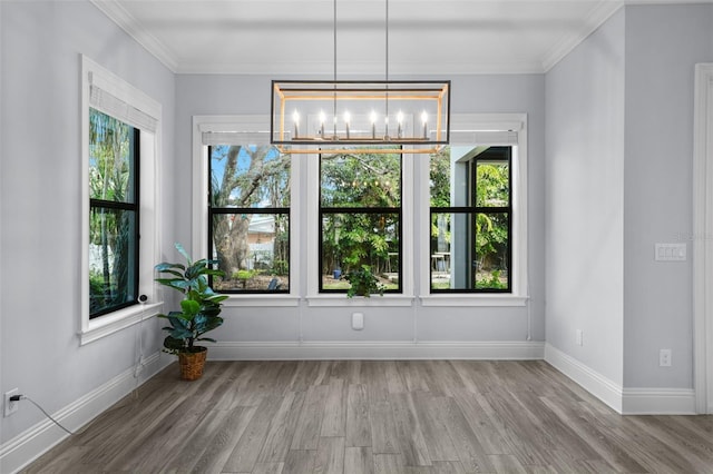 unfurnished dining area featuring an inviting chandelier, ornamental molding, plenty of natural light, and hardwood / wood-style flooring