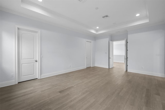 unfurnished room featuring hardwood / wood-style flooring, crown molding, and a raised ceiling