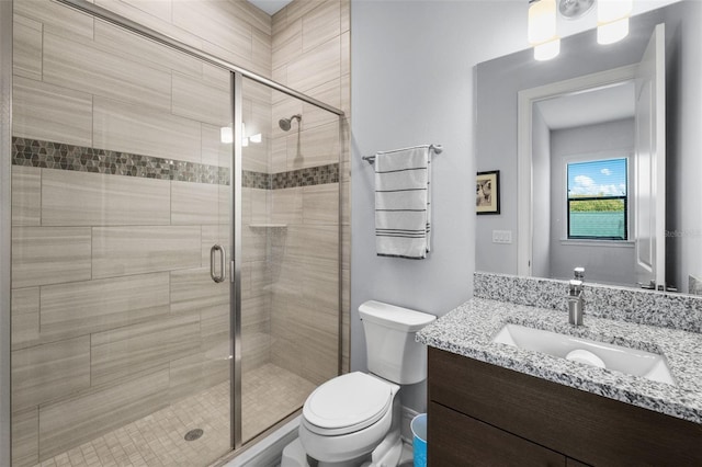 bathroom featuring vanity, a shower with door, and toilet