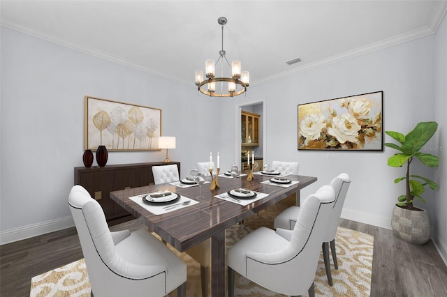 dining area with dark wood-type flooring, ornamental molding, and a chandelier