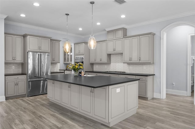 kitchen featuring appliances with stainless steel finishes, a center island, gray cabinetry, and decorative light fixtures