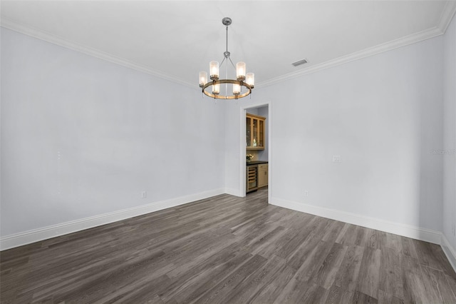 empty room with dark hardwood / wood-style flooring, a notable chandelier, and ornamental molding