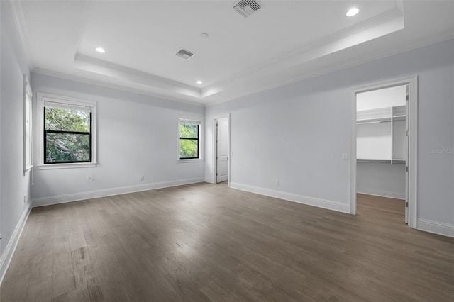 spare room featuring a raised ceiling, ornamental molding, and dark hardwood / wood-style flooring